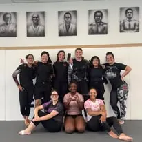 Women’s Jiu-Jitsu team posing together on the mats after class